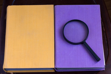 two closed books and a magnifying glass