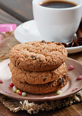 Cookies with chocolate and fragrant coffee with spices on an old wooden background.