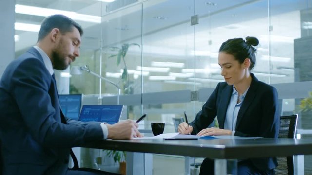 In the Office Businesswoman and Businessman Have Conversation Draw up a Contract, Sign Documents, Seal the Deal, Finish Transaction, Shake Hands. Shot on RED EPIC-W 8K Helium Cinema Camera.