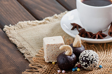Fototapeta na wymiar Chocolate sesame sweets and aromatic coffee with spices on an old wooden background.