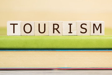 Tourism word built with letter cubes on green book