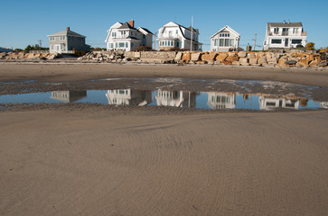 A row of cottages along the beach reflected in the water at low tide