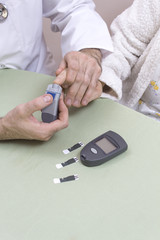 1.	Lekarz nakłuwa palec bardzo starej kobiety. Glukometr z paskami leży na stole.