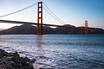 Golden Gate bridge at dawn with calm water and pink sky, San Francisco, California