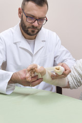 Dłonie lekarza zakładają opatrunek z bandaża na dłoń kobiety