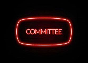 Committee neon sign on brick wall background.