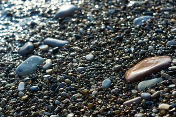 pebble stones on the sea beach, the rolling waves of the sea with foam