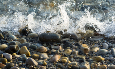pebble stones on the sea beach, the rolling waves of the sea with foam
