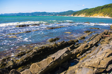 rocky sea shore with pebble beach, waves with foam