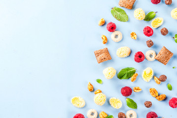 Healthy breakfast ingredients concept. Various breakfast cereal, raspberries and mint on blue background, copy space top view