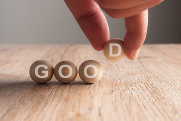 Hand putting on good word written in wooden cube