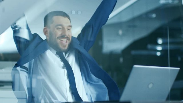 In the Office Businessman Sitting at the Desk Using Laptop Finishes Project and Wins Big. Makes Successful Gestures Raises Arms in Celebration. Shot on RED EPIC-W 8K Helium Cinema Camera.