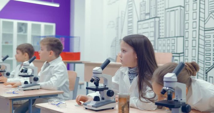 Children in a biology class. On the table are microscopes