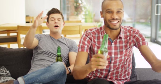 4k, Young male friends watching sports on TV. One celebrates while other sulks as his team lost the match