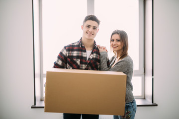 Young happy couple holding cardboard boxes and moving to new place