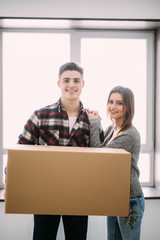 Young happy couple holding cardboard boxes and moving to new place