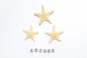 Fototapeta na wymiar Three starfish on a white background with an inscription voyage