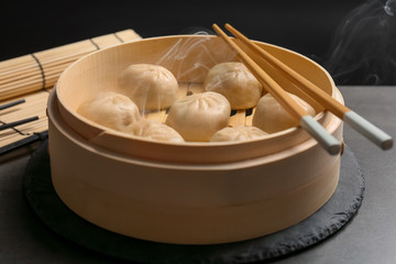Fototapeta na wymiar Bamboo steamer with tasty baozi dumplings on table