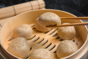 Fototapeta na wymiar Cooking tasty baozi dumplings on bamboo steamer, closeup