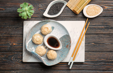 Plate with tasty baozi dumplings and soy sauce on table