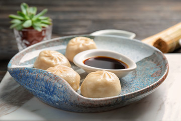 Obraz na płótnie Canvas Plate with tasty baozi dumplings and soy sauce on table