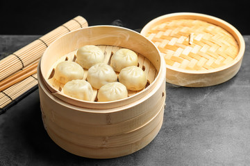 Bamboo steamer with tasty baozi dumplings on table