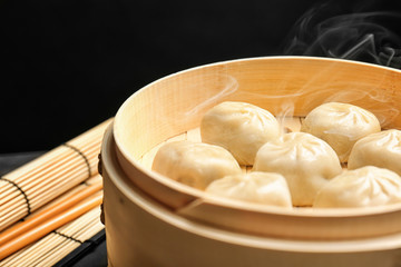 Bamboo steamer with tasty baozi dumplings on table, closeup