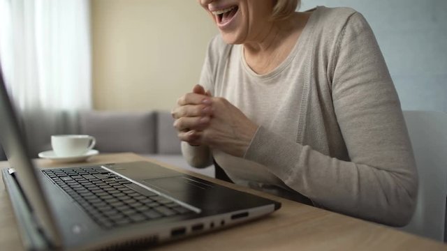 Smiling aged lady typing message on laptop, communicating on dating website