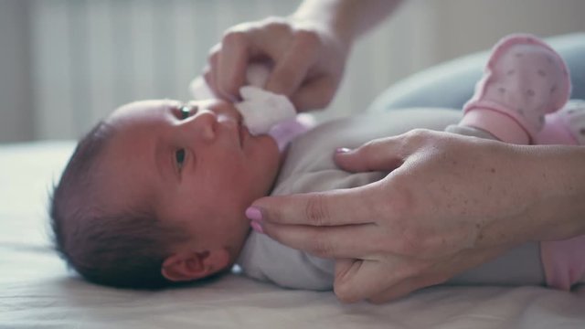 Hands cleaning mouth of newborn baby