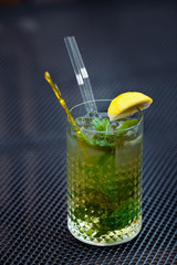 Mojito cocktail with lime and mint in highball glass on a grey table background. Copyspace