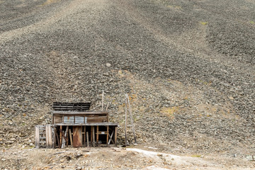 Old building used for the coal mining industry at Svalbard. Landscape of glacial moraine rocks in Longyear valley, Svalbard. Arctic landscape.