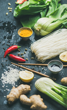 Asian cuisine ingredients over slate stone background. Vegetables, spices, shrimp, rice, sauces for cooking vietnamese, thai or chinese food. Clean eating, veretarian food concept