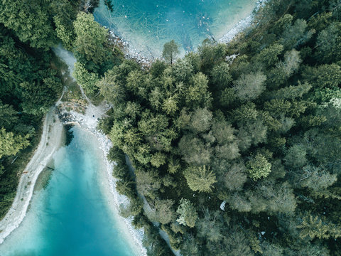 Aerial drone shot of a natural bay in lake Eibsee, Germany during a summer morning with pine forest