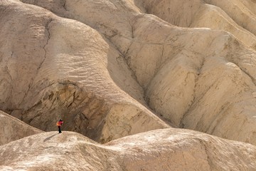 Photographer in red jacket is minimized by vast desert landscape