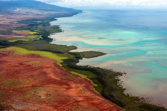 Aerial view of the colorful coast and Pacific water of the island of Molokai, Hawaii, shot from a small, low-flying prop plane