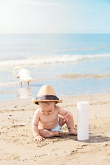 Fototapeta na wymiar happy kid with dad hat playing with sand on beach