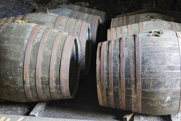 Aging old wooden barrels and casks in cellar at whisky distillery in Scotland