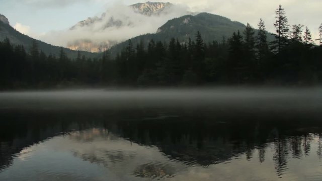 Fog floating over Gruenersee Green lake in Tragoss, Styria, Austria Alps with mountain forest background