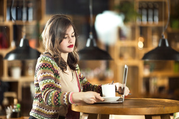Portrait of a young woman using laptop in cafe