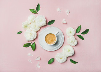 Obraz na płótnie Canvas Spring morning concept. Flat-lay of cup of freshly brewed coffee surrounded with white ranunculus flowers and petals over light pink pastel background, top view