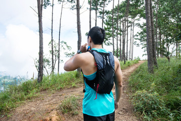 Bottle of energy drink and water in hands of trail runner.