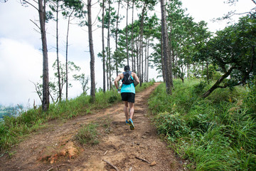 Athletic runner running on tropical forest trail, dramatic tone