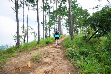 Athletic runner running on tropical forest trail, dramatic tone