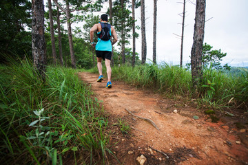 Athletic runner running on tropical forest trail, dramatic tone