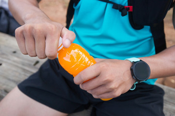 Bottle of orange juice in hands of trail runner visitor