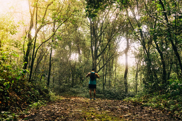 Athletic runner running on tropical forest trail, dramatic tone