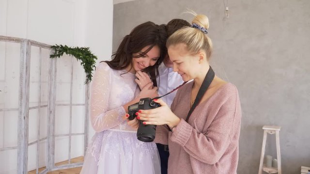 A professional photographer shows the result of their teamwork of a family photo shoot that the couple are very happy and looks at the photos on the camera