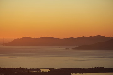 Obraz premium Sunset in the Bay Area San Francisco over bay and with bridge and city