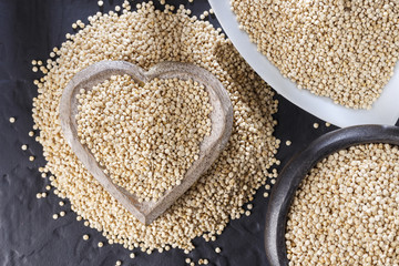 Quinoa grains with spoon and bowl on black background