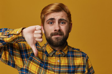 Studio shot of stylish, bearded male with dyed blond gold hair shows sign of dislike. Negative...